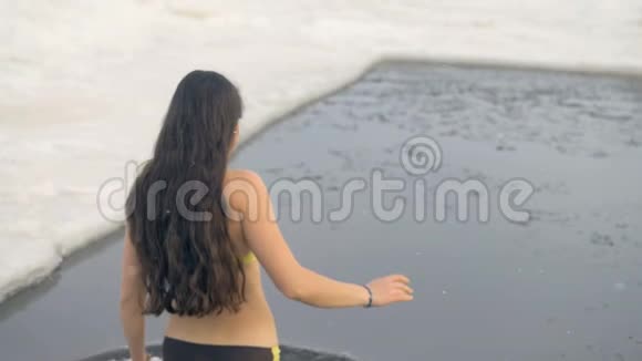 一个穿着泳衣的女人在冰冻的水中慢慢地走着视频的预览图