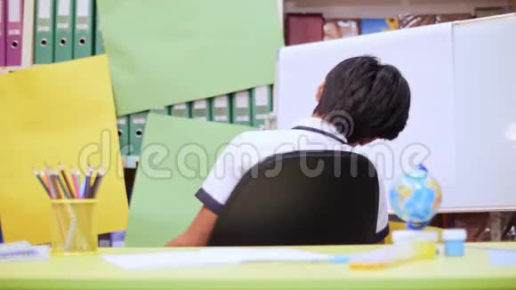 一个男孩躺在椅子上拿起一支铅笔在笔记本上写一些东西视频的预览图