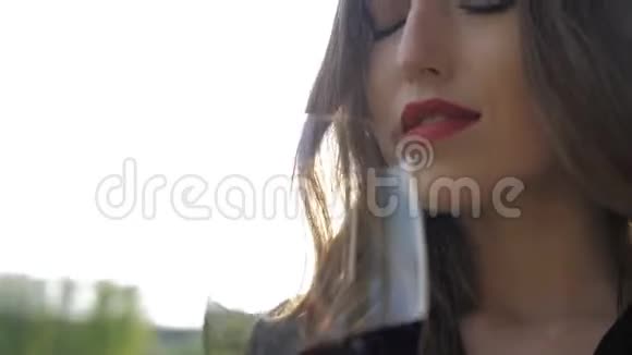 年轻性感的女孩红唇在大自然的背景上旋转着一杯红酒视频的预览图