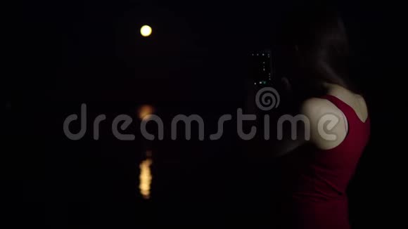 一个年轻的女人在河边拍红月亮视频的预览图