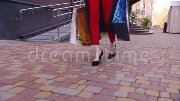 时髦的女人带着购物袋走在人行道上在图片中只能看到腿视频的预览图