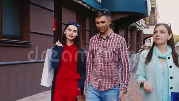 朋友两个女人和一个男人带着购物袋走在街上视频的预览图