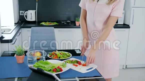 在厨房做蔬菜沙拉的时候年轻的女人会用耳机跳舞听音乐视频的预览图