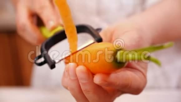 女人的手剥去新鲜的胡萝卜特写镜头视频的预览图