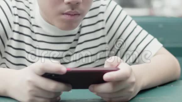 亚洲十几岁的男孩在路边玩手机游戏满脸兴奋视频的预览图