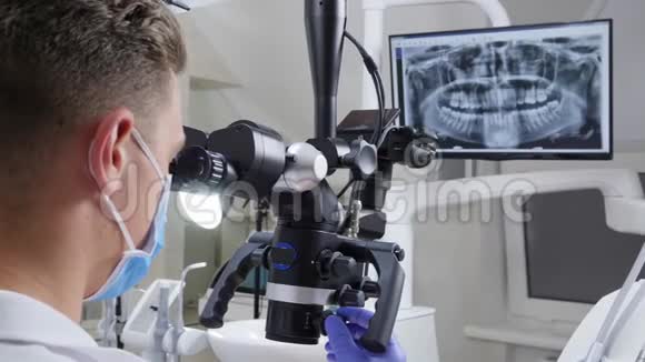 医用面罩中的牙科医生调整双眼显微镜工作在屏幕上显示颌骨视频的预览图