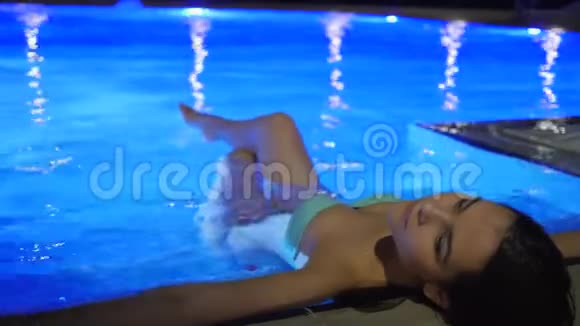 暑假晚上女性进入彩色游泳池的奢华假期视频的预览图