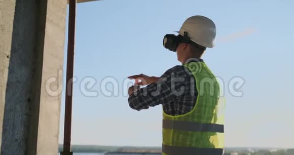 工程师建筑屋顶上的建筑工人站在vr眼镜里用它的界面移动他的手视频的预览图