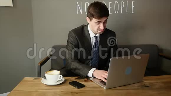 英俊的商人厌倦了在咖啡馆用笔记本电脑工作视频的预览图