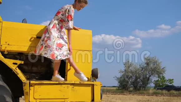 穿着衣服的农村女孩在天空背景下的联合收割机的帽子上空中亲吻视频的预览图