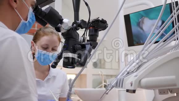 医生在显微镜下观察用专业工具做手术附近站着女实验室助理进入视频的预览图