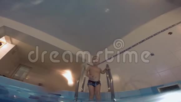 一家人正在游泳池里游泳一个小儿子从水池的桥上跳进水里成功了视频的预览图