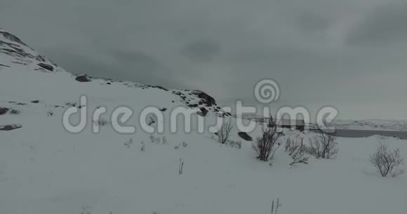 白雪山脚下有一座房子在灰色的天空下被解冻的海湾包围着视频的预览图