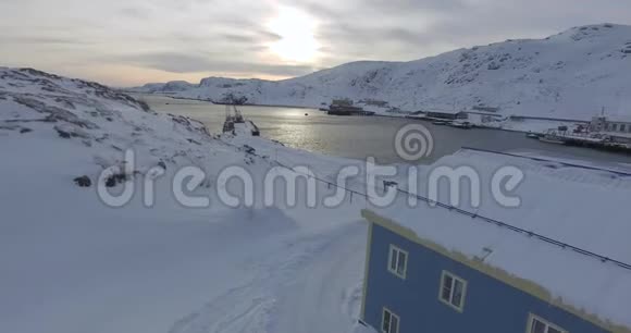 阳光照耀下的海湾有蓝色房子的雪景视频的预览图