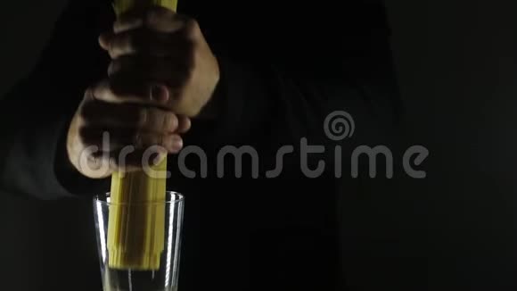 男人把金色的生面条放在深黑的背景上视频的预览图