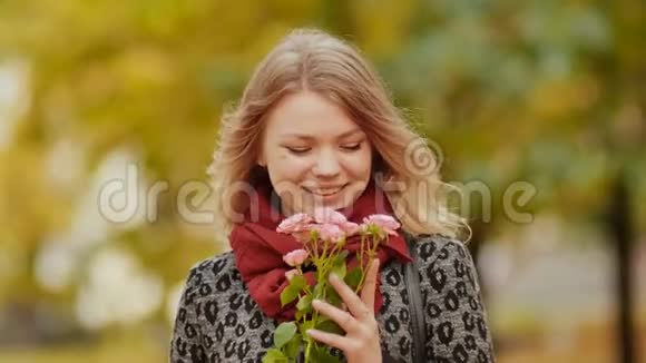 迷人的年轻和快乐的女孩与一束粉红色的花在秋天的城市公园视频的预览图