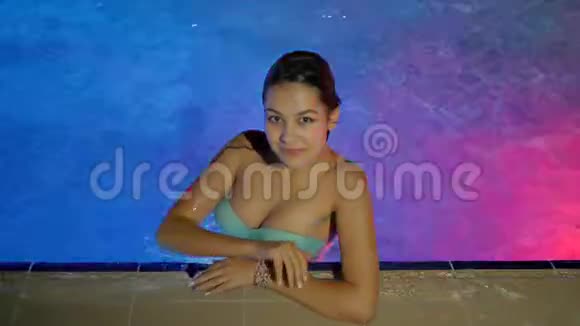 湿漉漉的女孩在晚上放松到游泳池在奢华的周末竖起大拇指视频的预览图