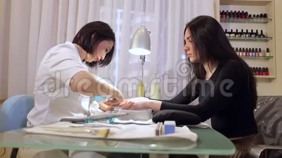 美甲师为年轻女性做美甲指甲护理视频的预览图