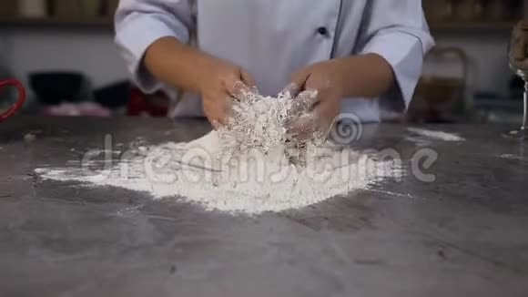 糖果师一边揉面一边把水和面粉混合在桌子上视频的预览图