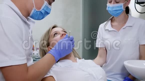 牙科镜检查坐在椅子上的年轻女子的牙齿视频的预览图