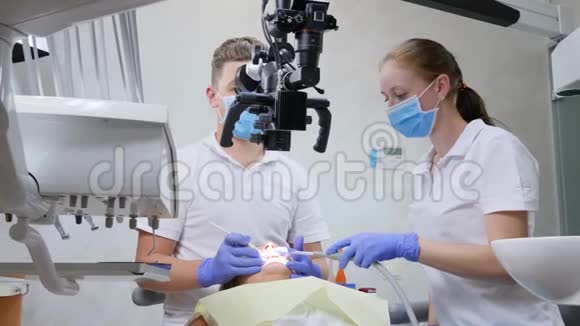 专家助手使用光学显微镜对牙科室躺卧病人口腔进行手术视频的预览图