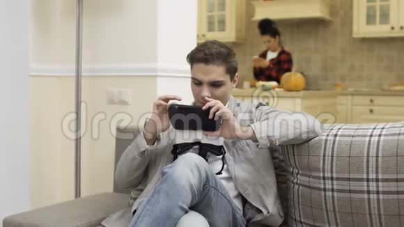 年轻人用虚拟现实眼镜坐在房间的沙发上视频的预览图