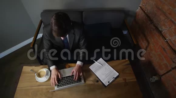 一个坐在咖啡馆里用笔记本电脑工作的年轻人关闭了他的笔记本电脑然后走了视频的预览图