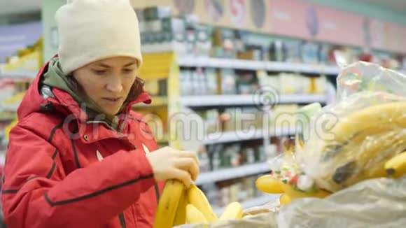 穿红色夹克的女人在超市买香蕉视频的预览图