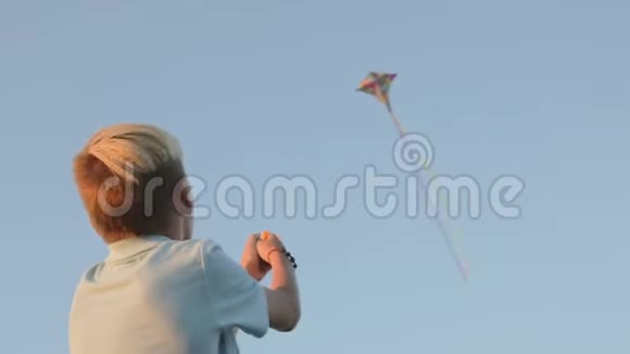 一个男孩在大风中放风筝在背景中风筝在天空中飞翔视频的预览图