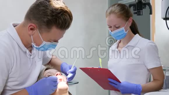 医疗检查医生手里拿着牙镜看着女性牙齿旁边的员工把诊断写在视频的预览图