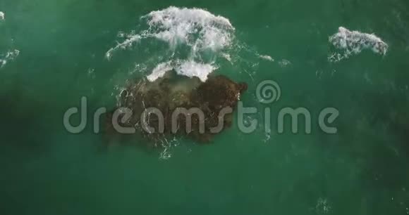 无人机锁定拍摄的透明绿色波浪冲洗在美丽的海洋附近的海岸与泡沫碰撞视频的预览图