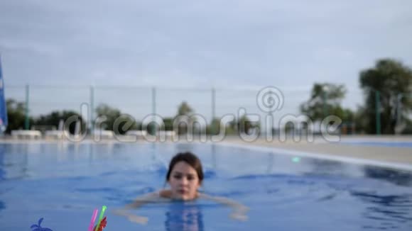 年轻女子在假期露天游泳池喝含酒精饮料和休息视频的预览图