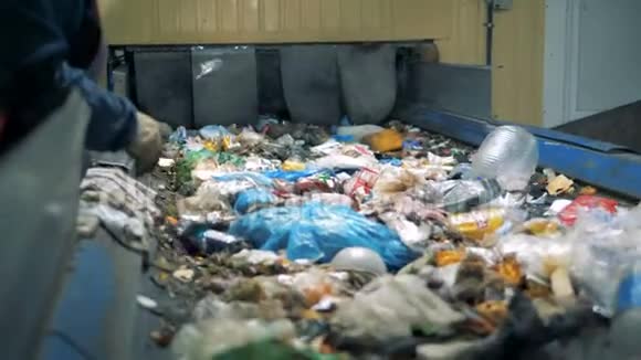 垃圾回收厂一个戴手套的人从废物分类工厂的移动线路中挑选不可回收的垃圾视频的预览图