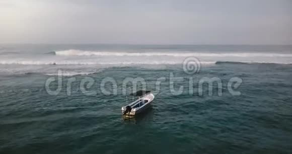 无人机在小船和海浪之上飞行回头在海岸上露出壮丽的热带度假屋视频的预览图