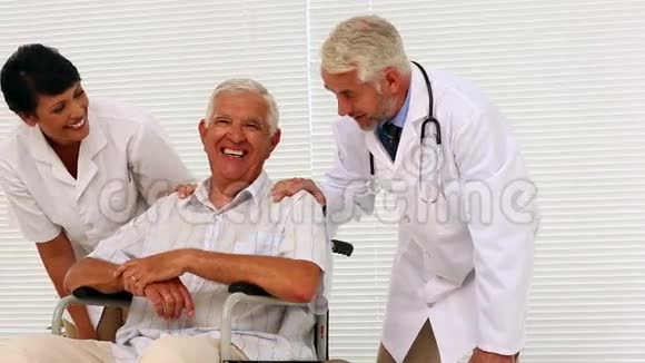 医生和护士与坐轮椅的老年病人交谈视频的预览图