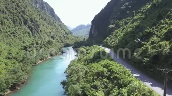 柏油路蜿蜒在青山峡谷的绿色河流上视频的预览图