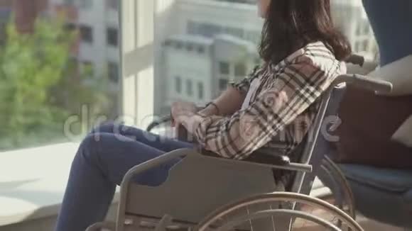坐在窗边坐在轮椅上的孤独残疾女孩视频的预览图