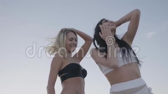 两个活泼有趣的女孩正在户外天空背景下跳舞和开玩笑视频的预览图