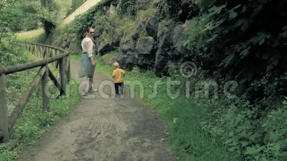 4k慢动作美丽的年轻家庭母亲和儿子沿着风景如画的风景优美的海滨泥炭路散步视频的预览图