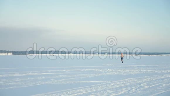一个裸胸男子在远处冰冻的河流上奔跑的剪影4K视频的预览图