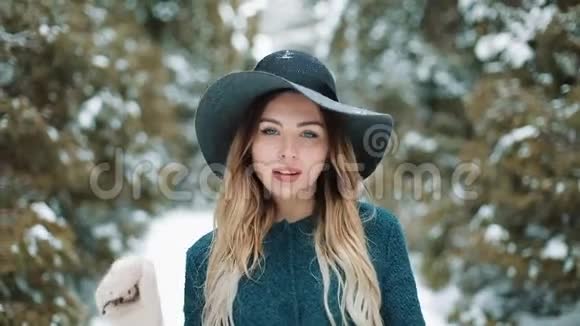 穿着绿色外套和帽子的女士在冬天的森林里走来走去特写一幅年轻貌美的年轻女子的肖像视频的预览图