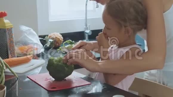 年轻的母亲在家庭厨房教她的小女儿做饭视频的预览图