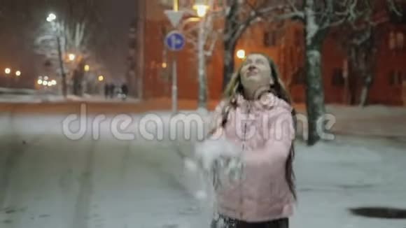 冬天城市里一个年轻快乐的女人的肖像那个女孩走在街上喜欢下雪视频的预览图