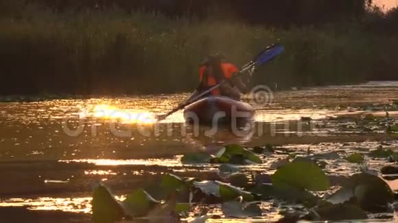 在夕阳下皮划艇上的人们在河上漂浮视频的预览图