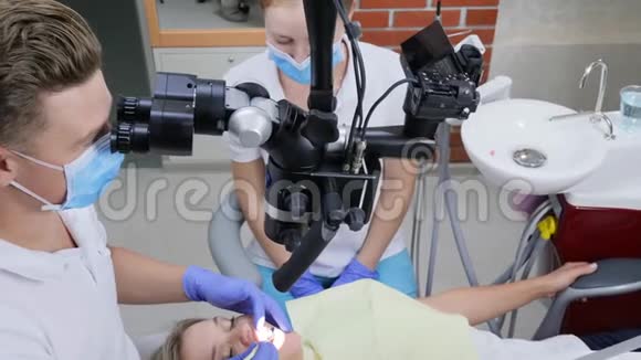 医学检查现代显微镜专家正在为牙齿疼痛的妇女做手术视频的预览图