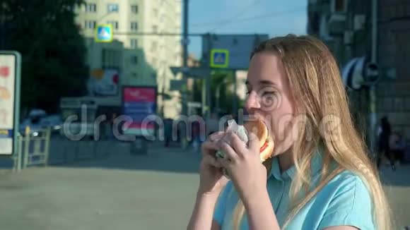 特写镜头拍摄一个女孩在街上吃汉堡包视频的预览图