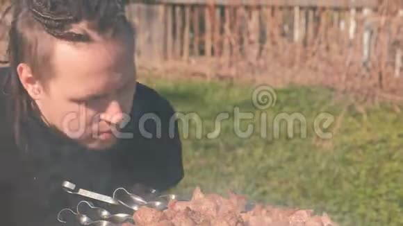 头发上有恐惧的年轻人在后院的炭炭火烤架上烹制沙石肉视频的预览图