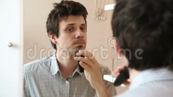 机刮脸发年轻的帅哥用电动刮胡子张开嘴视频的预览图