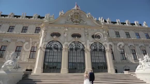 美丽的年轻新娘和她英俊的新郎在贝维迪尔宫散步高清视频视频的预览图