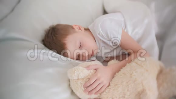 七岁的男孩抱着玩具熊睡着了视频的预览图